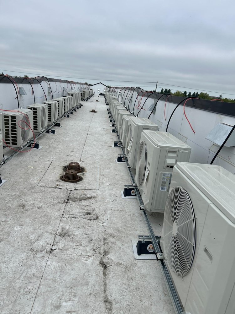 Compact outdoor HVAC units lined up along both sides of a rooftop walkway.