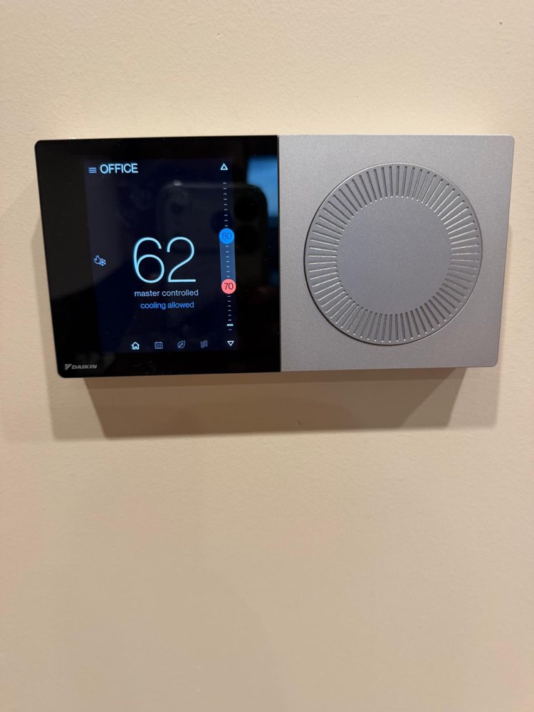 Daikin wall-mounted temperature controller with a black display and a large silver dial.