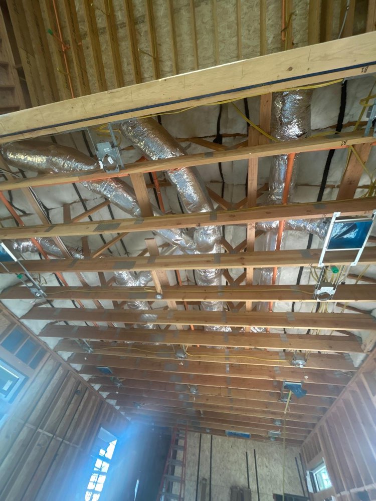 Silver insulated air ducts and rectangular openings within exposed wood ceiling framing.