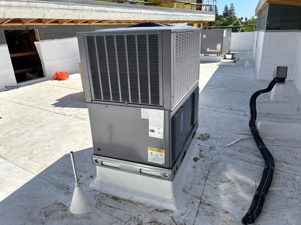 Large gray outdoor HVAC unit on a rooftop base, with another unit behind it.